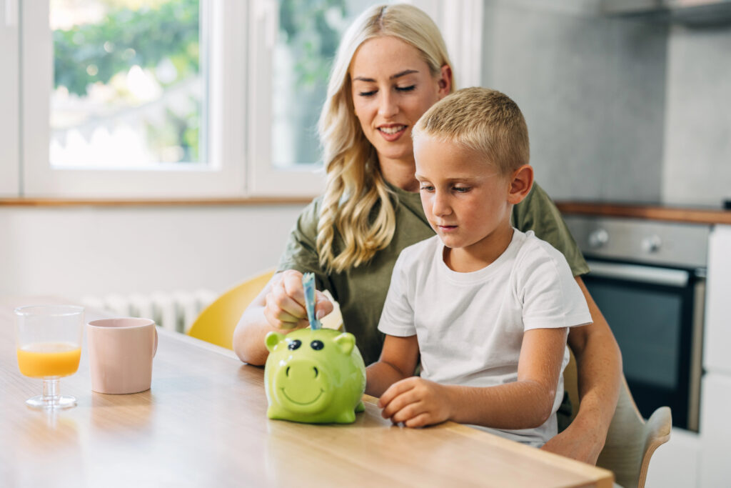 Elternteil mit Kind, Sparschwein, warmes Licht